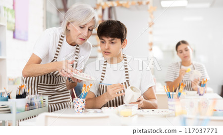 Experienced female ceramicist teaching enthusiastic guy to paint pottery Experienced female ceramicist teaching enthusiastic guy to paint pottery 117037771