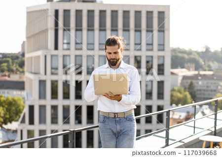 Young professional working on laptop on rooftop terrace Young professional working on laptop on rooftop terrace 117039668
