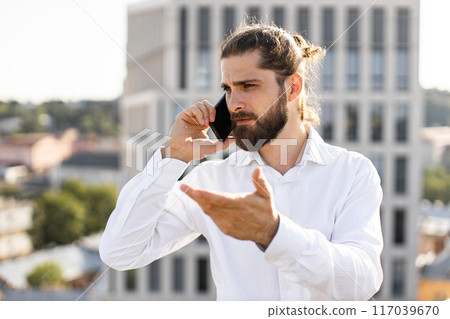 Young businessman talking on smartphone outdoors downtown in sunny weather Young businessman talking on smartphone outdoors downtown in sunny weather 117039670