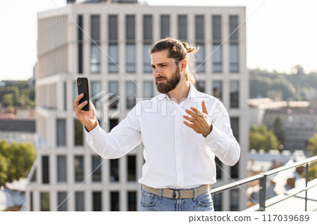 Businessman having a video call on rooftop in urban setting 117039689