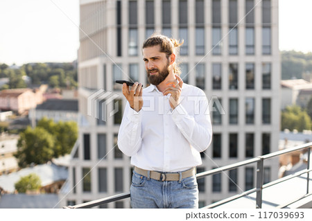 Businessman using smartphone on rooftop with urban background Businessman using smartphone on rooftop with urban background 117039693