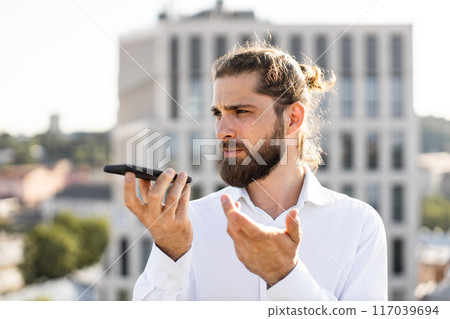 Businessman using smartphone outdoors on rooftop during workday 117039694
