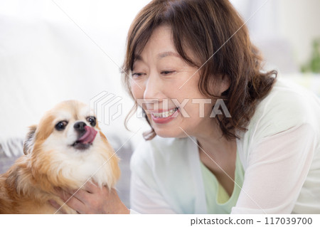 Senior woman relaxing with her pet dog Senior woman relaxing with her pet dog 117039700