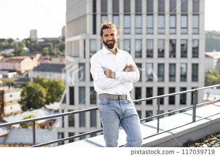 Confident businessman standing on rooftop with city view Confident businessman standing on rooftop with city view 117039719