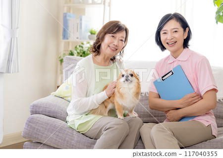 護理:高級婦女和護理人員在沙發上撫摸狗 護理:高級婦女和護理人員在沙發上撫摸狗 117040355