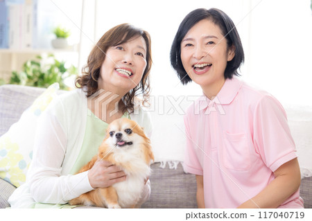 護理：高級婦女和護理人員在沙發上撫摸狗 117040719