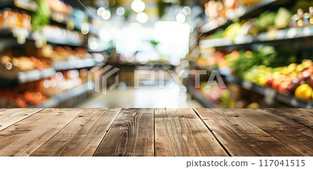 Empty wooden tabletop in front of colorful, blurred vegetable aisle in grocery store, perfect for displaying a product or advertising. Banner, copy space 117041515