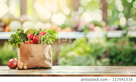 Paper bag with fresh vegetables including lettuce, tomatoes, onions and broccoli on a wooden table with a blurred garden background Paper bag with fresh vegetables including lettuce, tomatoes, onions and broccoli on a wooden table with a blurred garden background 117041516