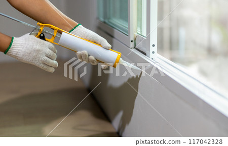 Construction worker using silicone sealant caulk the outside window frame. Construction worker using silicone sealant caulk the outside window frame. 117042328