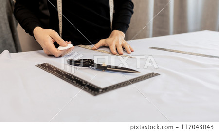 Tailor working at table in workshop 117043043
