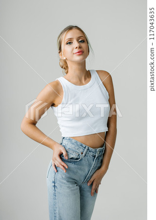 Young caucasian woman is wearing a white top and blue jeans Young caucasian woman is wearing a white top and blue jeans 117043635