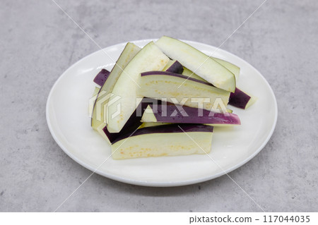 Summer vegetable eggplant cut into rectangles. The cut eggplant is placed on a round plate. Summer vegetable eggplant cut into rectangles. The cut eggplant is placed on a round plate. 117044035
