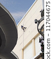 Worker on Ropes Painting Building Exterior. 117044675