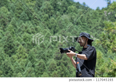 A man holding a camera in nature 117045193