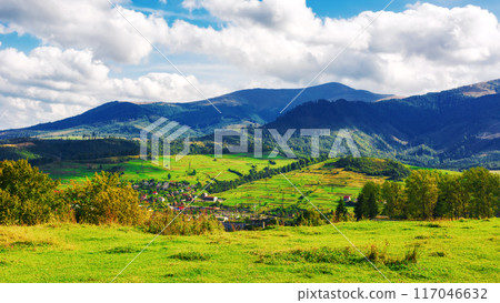 mountainous countryside landscape of ukraine. view in to the distant rural valley from meadow. trees on the hills of carpathian borzhava ridge. sunny weather, clouds on the sky. volovets district 117046632