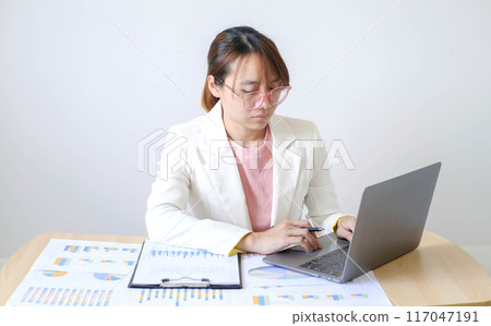Asian businesswoman sit at their desks and calculate financial graphs showing results about their investments and plan successful business growth process Asian businesswoman sit at their desks and calculate financial graphs showing results about their investments and plan successful business growth process 117047191