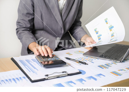 Asian businesswoman sit at their desks and calculate financial graphs showing results about their investments and plan successful business growth process Asian businesswoman sit at their desks and calculate financial graphs showing results about their investments and plan successful business growth process 117047229