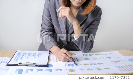 Asian businesswoman sit at their desks and calculate financial graphs showing results about their investments and plan successful business growth process 117047231