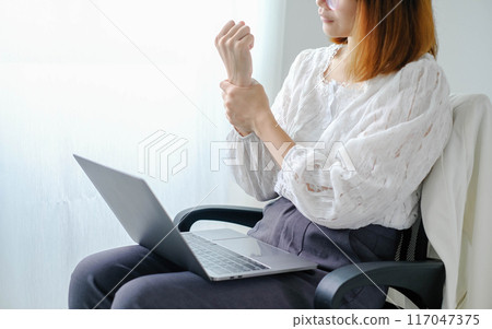 Woman hand with wrist pain numbness and pain in the palm of the hand has pain and tingling in the nerve endings This is a side effect of sitting and working for a long time on a laptop at the office Woman hand with wrist pain numbness and pain in the palm of the hand has pain and tingling in the nerve endings This is a side effect of sitting and working for a long time on a laptop at the office 117047375