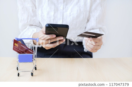 Asian girl shopping online holding credit and using smartphone enter their card number in the mobile phone app to purchase and payment in internet store Asian girl shopping online holding credit and using smartphone enter their card number in the mobile phone app to purchase and payment in internet store 117047379