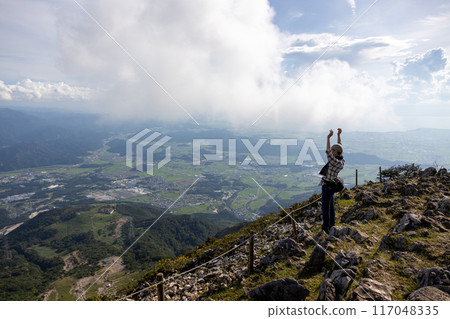 一位戴著帽子和毛巾的老人爬上伊吹山,張開雙臂眺望風景 一位戴著帽子和毛巾的老人爬上伊吹山,張開雙臂眺望風景 117048335