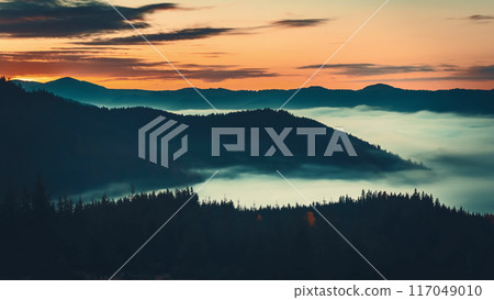 The sun's first rays light up carpathian peaks, casting shadows on slopes with fog adding mystery and serenity The sun's first rays light up carpathian peaks, casting shadows on slopes with fog adding mystery and serenity 117049010