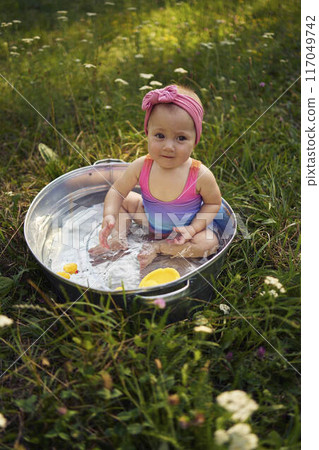baby in a metal tub plays with rubber ducklings in the summer garden baby in a metal tub plays with rubber ducklings in the summer garden 117049742