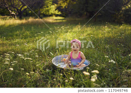 baby in a metal tub plays with rubber ducklings in the summer garden baby in a metal tub plays with rubber ducklings in the summer garden 117049746