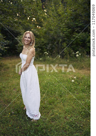 portrait of a beautiful 30-year-old woman in a white dress in the garden portrait of a beautiful 30-year-old woman in a white dress in the garden 117049869