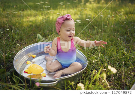 baby in a metal tub plays with rubber ducklings in the summer garden baby in a metal tub plays with rubber ducklings in the summer garden 117049872
