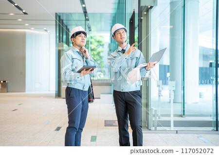 Businessmen wearing work clothes having a meeting at a construction site 117052072