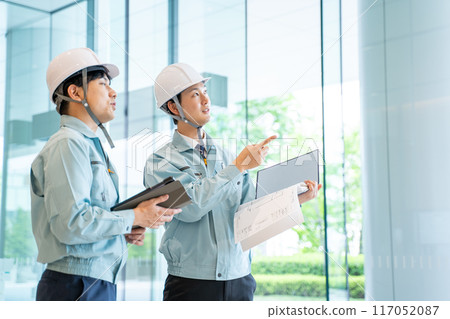 Businessmen wearing work clothes having a meeting at a construction site 117052087