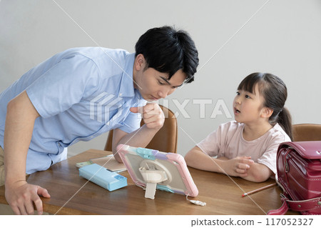 A tutor teaching a student while looking at a tablet A tutor teaching a student while looking at a tablet 117052327