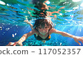 A girl swimming towards us with her eyes open in the water 117052357