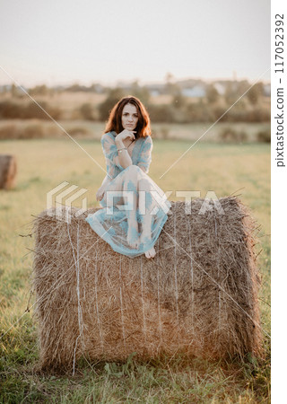 sexy young topless nude girl sitting on haystack in field in summer. Added the effect of a small film grain 117052392