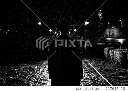 dark silhouette of a man in a hat in the rain on a night street in a city dark silhouette of a man in a hat in the rain on a night street in a city 117052410