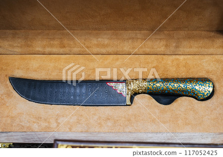 traditional oriental Uzbek knife made of Damascus steel in a wooden gift box in souvenir shop in Uzbekistan 117052425