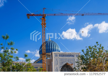 The Center of Islamic Civilization in Tashkent in Uzbekistan. Crane on construction site builds a new large mosque in summer on background of blue sky The Center of Islamic Civilization in Tashkent in Uzbekistan. Crane on construction site builds a new large mosque in summer on background of blue sky 117052577