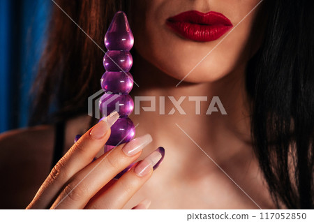 sexy girl holds a silicone butt anal plug in hands for masturbation and orgasm. A woman in lingerie with a sex toy for anal orgasm in bedroom 117052850
