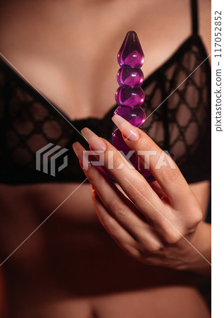 sexy girl holds a silicone butt anal plug in hands for masturbation and orgasm. A woman in lingerie with a sex toy for anal orgasm in bedroom 117052852