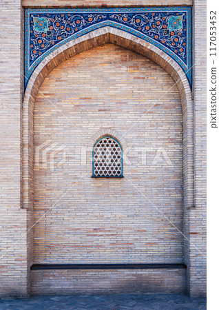 ancient ceramic tile with traditional Uzbek ornament Arabic Islamic pattern on wall with window of medieval Muslim mosque Hazrati Imam ancient ceramic tile with traditional Uzbek ornament Arabic Islamic pattern on wall with window of medieval Muslim mosque Hazrati Imam 117053452