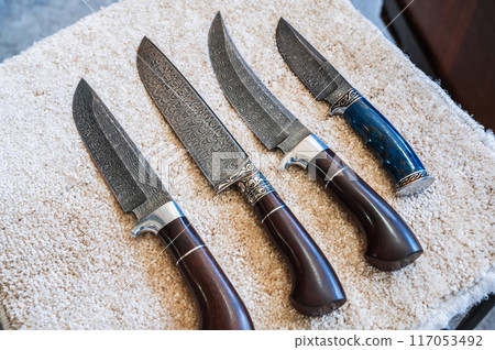 traditional oriental Uzbek chust knives made of Damascus steel with wooden handles in workshop in Uzbekistan 117053492