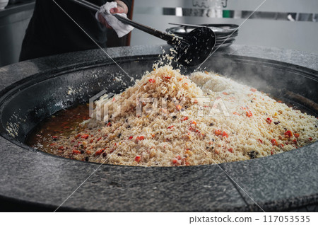 cooking traditional oriental Uzbek pilaf in a kazan in kitchen at the Tashkent Pilaf Center Besh Qozon in Uzbekistan 117053535