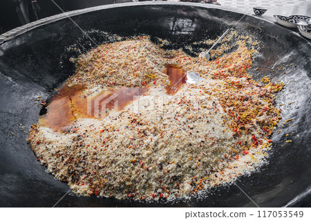 cooking Uzbek rice pilaf with spices and vegetables in big cauldron in Central Asian pilaf center in Tashkent in Uzbekistan 117053549