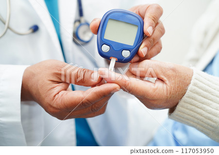 Asian doctor using digital glucose meter for check sample blood sugar level to treatment diabetes. 117053950
