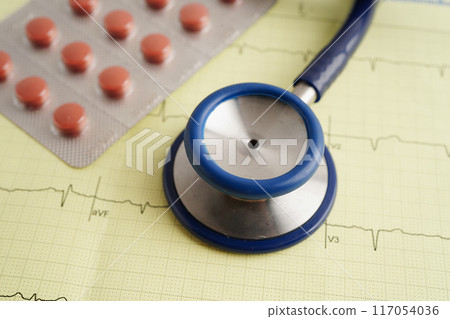 Stethoscope on electrocardiogram ECG with capsule drug, heart wave, heart attack, cardiogram report. Stethoscope on electrocardiogram ECG with capsule drug, heart wave, heart attack, cardiogram report. 117054036