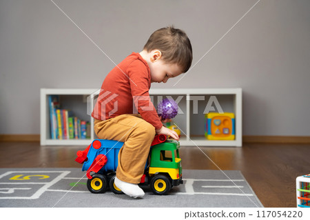 A small Caucasian toddler boy of 2 or 3 years old rides on a toy dump truck. Happy childhood concept A small Caucasian toddler boy of 2 or 3 years old rides on a toy dump truck. Happy childhood concept 117054220