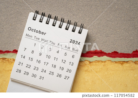October 2024 - small spiral desktop calendar against abstract paper landscape, time and business concept 117054582
