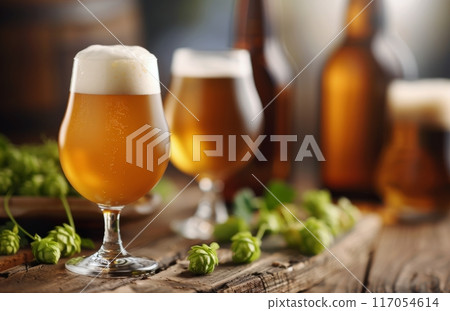 Craft Beer Glasses Surrounded by Fresh Hops on Rustic Wooden Surface 117054614