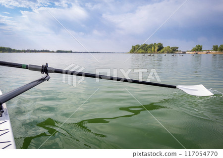 hatchet sculling oar and a rowing shell on a calm lake in summer, Boyd Lake in Colorado 117054770